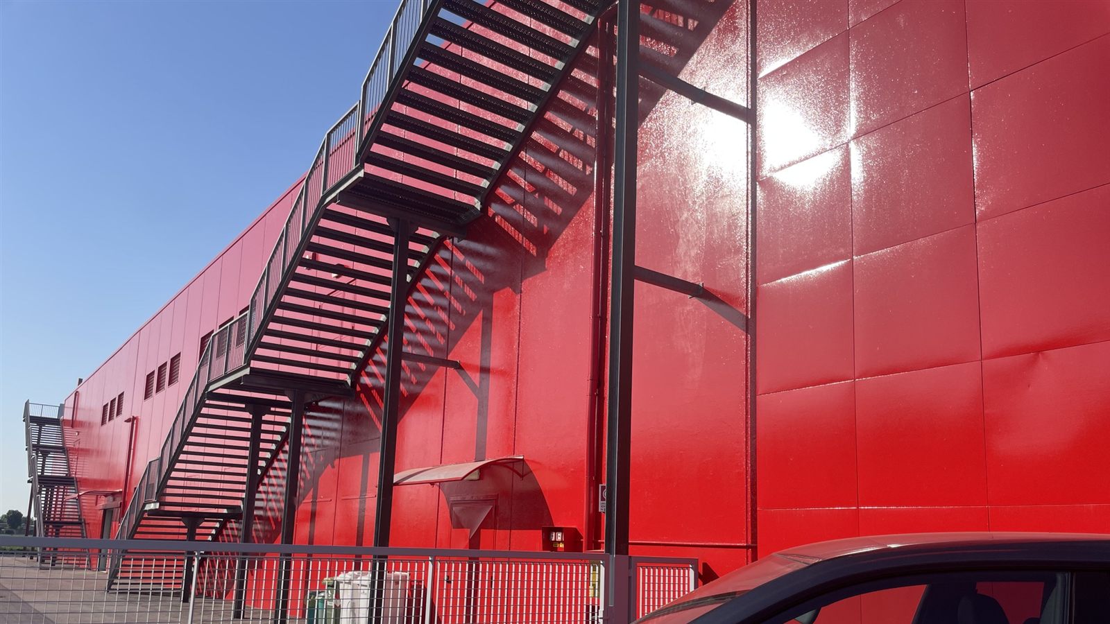 Facciata esterna di un edificio commerciale verniciata, con scala metallica di sicurezza