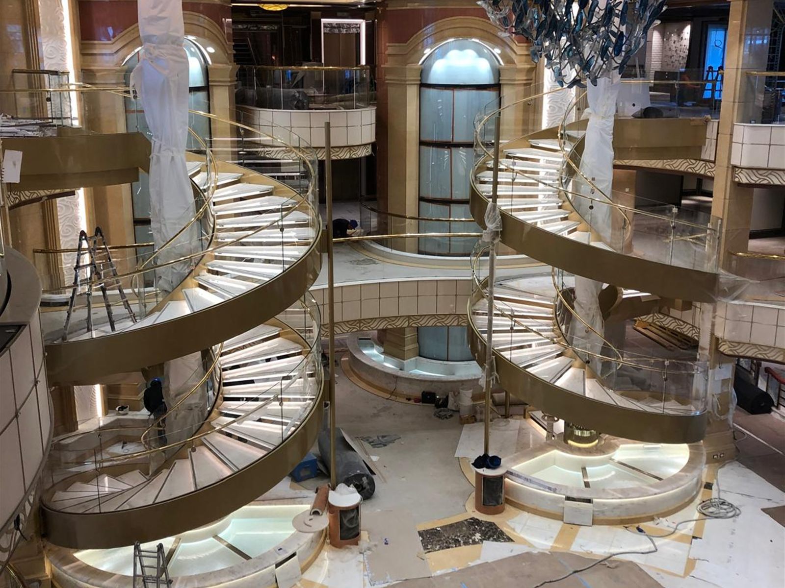Atrio di una nave da crociera in allestimento: scale elicoidali, colonne protette da teli e pavimenti mascherati